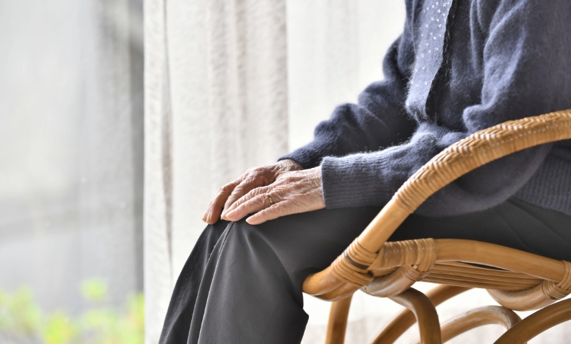 Senior woman sitting on a rattan chair on the porch